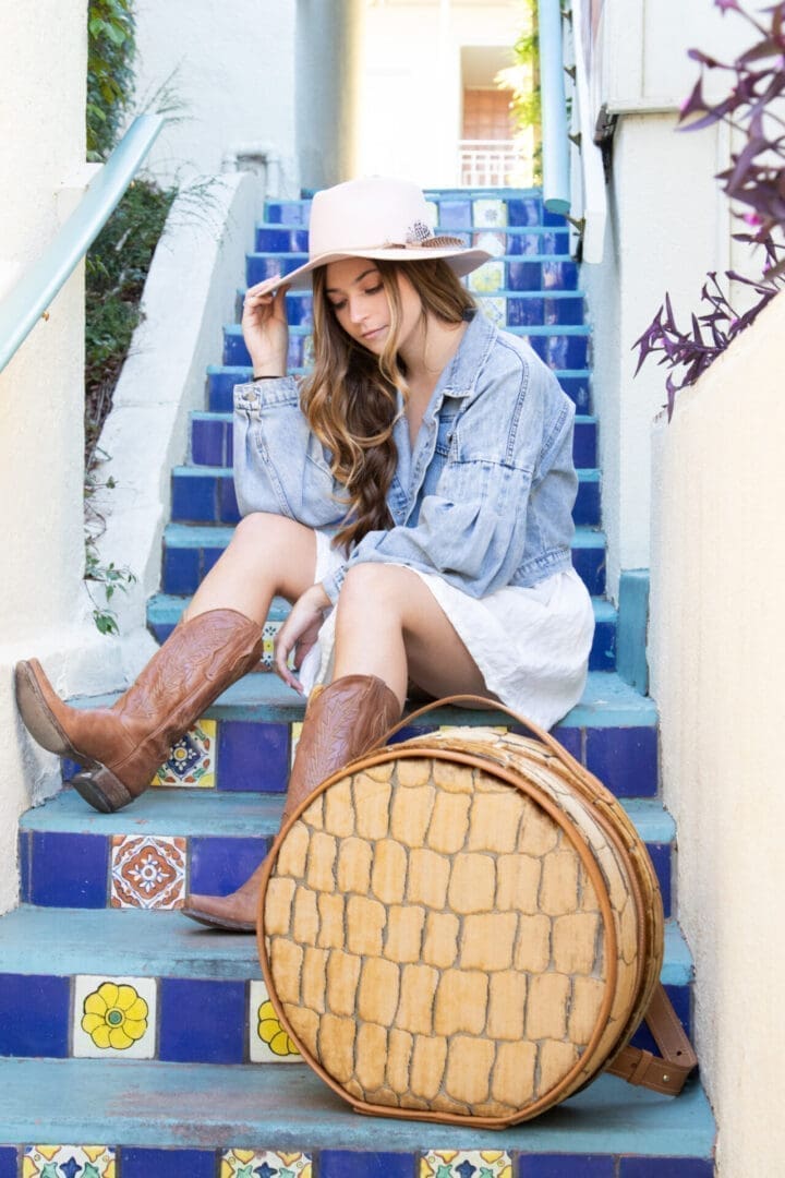 Woman in denim and boots with round bag.