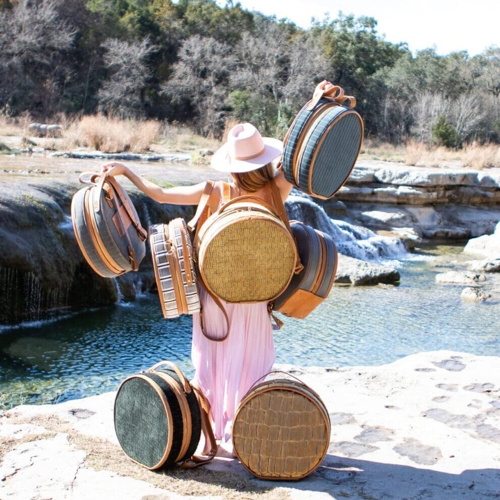 A person holding many drums in front of some water